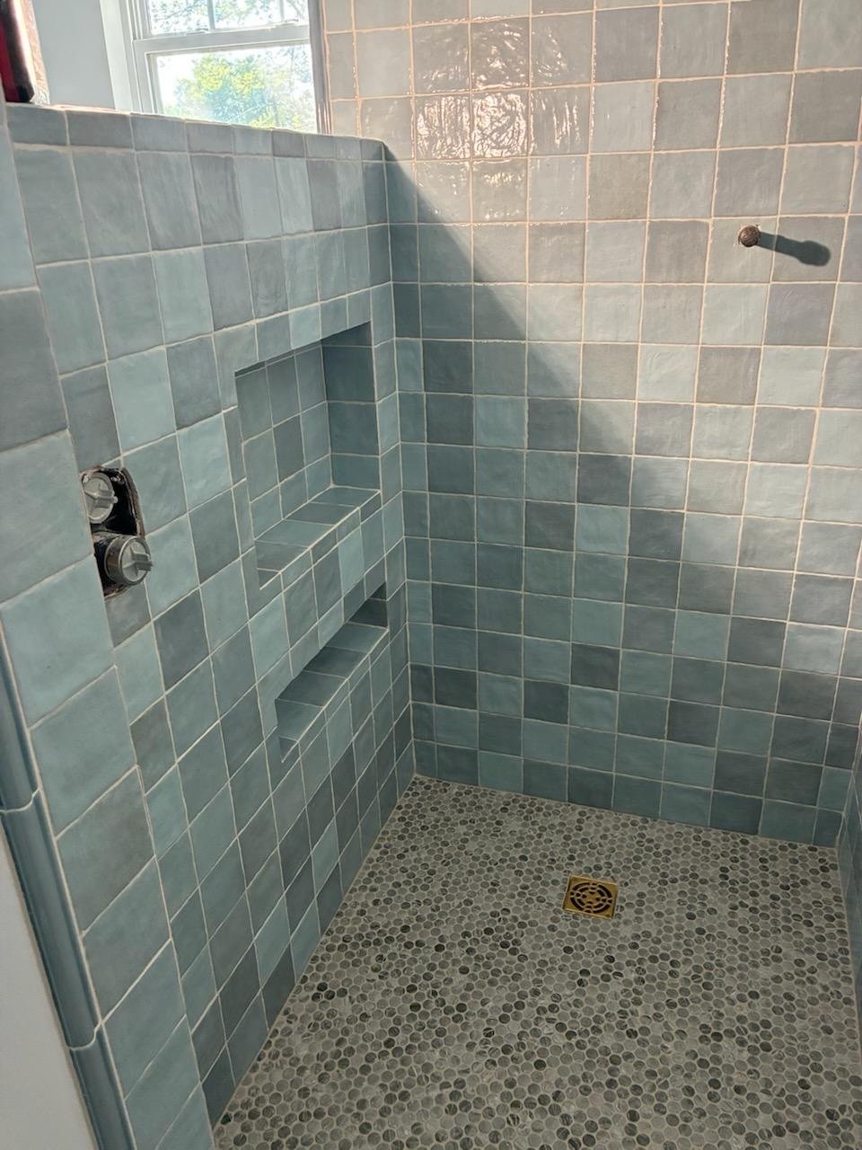 Bare subfloor &rarr; finished tile shower. ✨ We documented every step on this Nashville bathroom remodel &mdash; staggered backerboard, Schluter waterproofing, a prefab niche, and handmade-style wall tile set in a crisp running bond. The penny-tile shower floor with a brass drain is the detail that ties it all together. Swipe to see the build from the ground up. Ready to upgrade your bathroom? Drop us a message! 🚿🔵