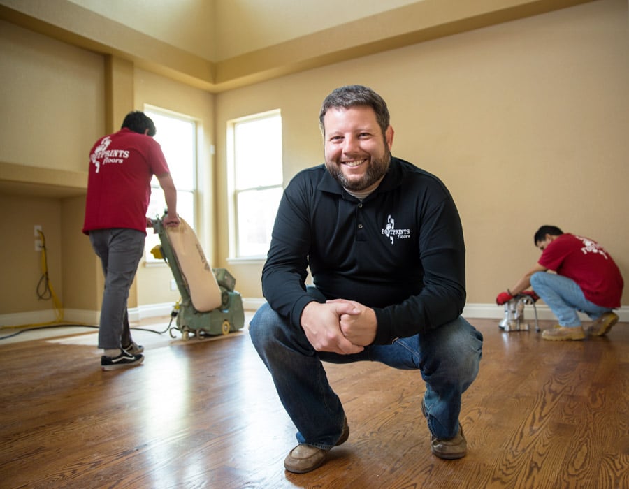 An image of the Footprints Floors CEO, Bryan Park, squatting in a newly renovated living room. 