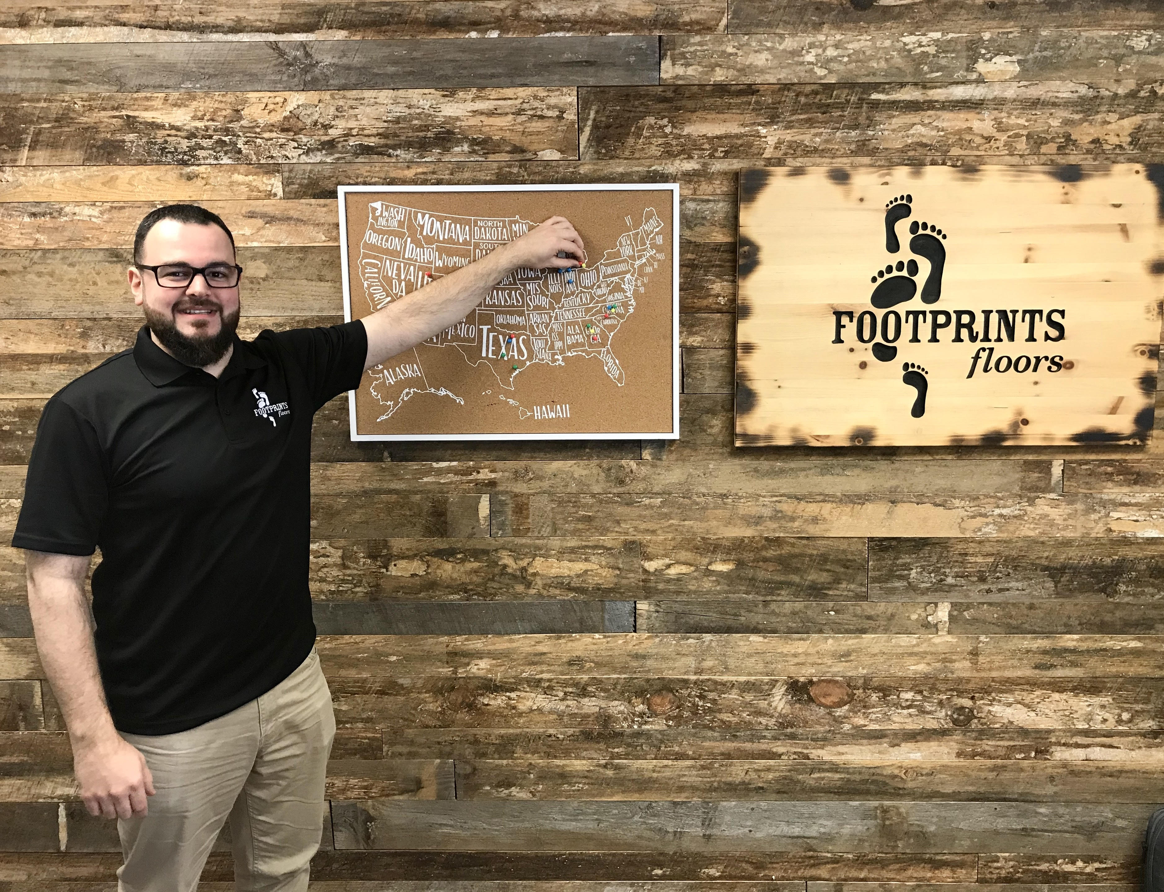 Adnan Alhaider standing in front of the Footprints Floors franchise map.