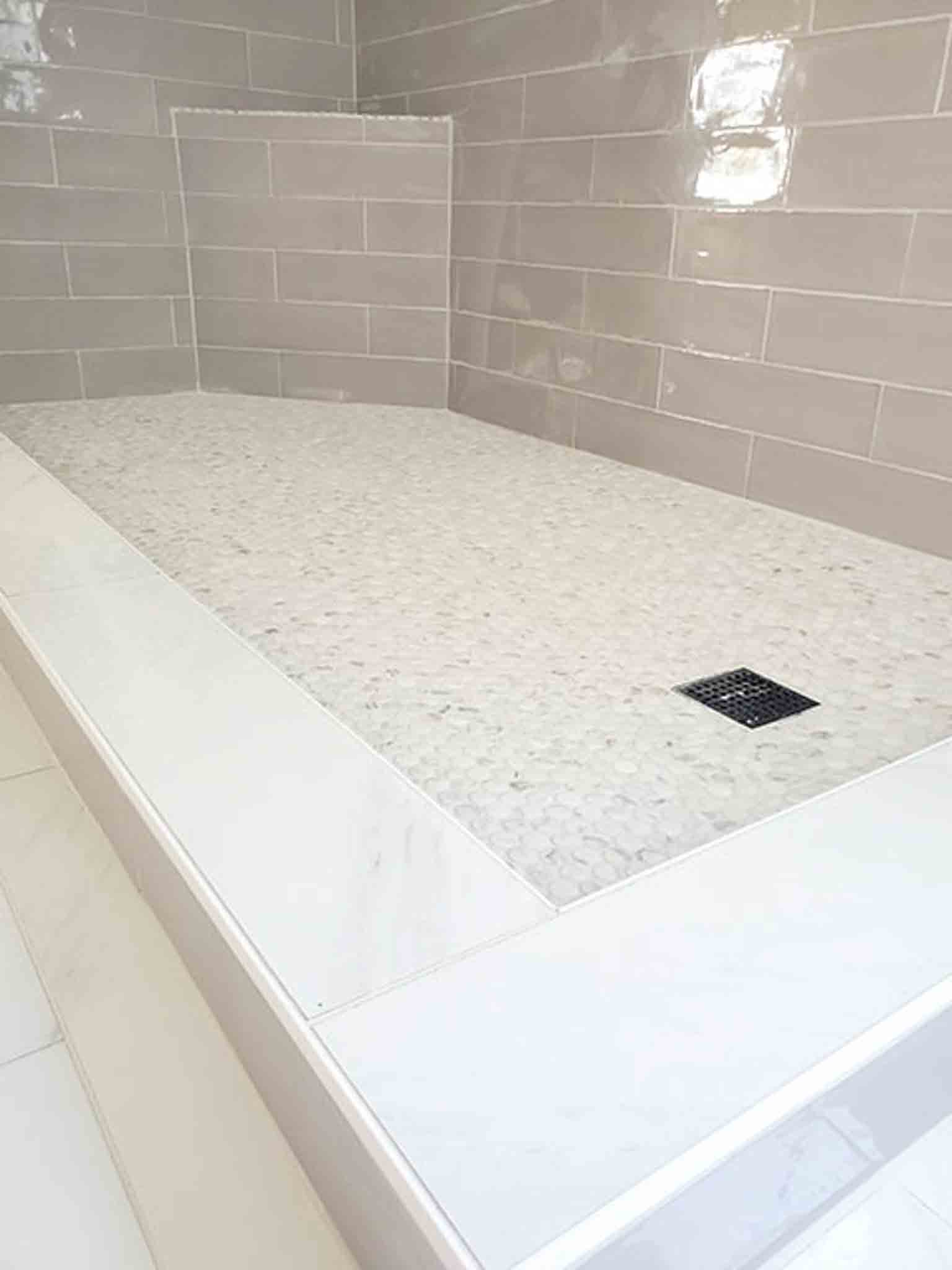 A stand up shower with white tiles.