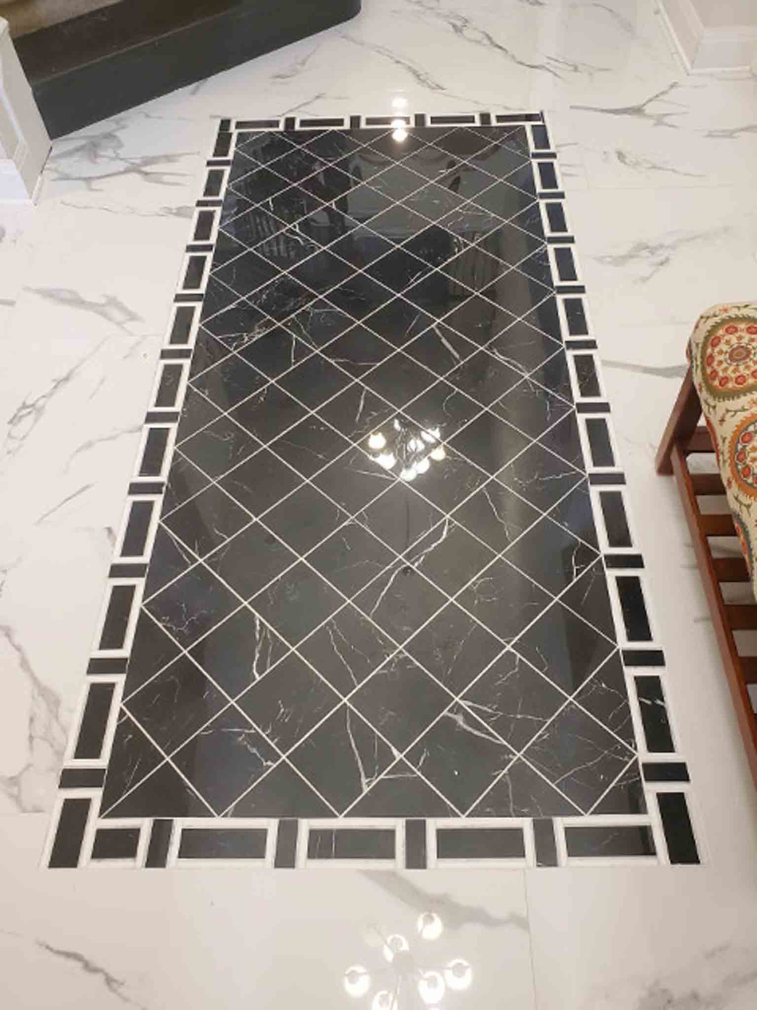 A black tile design in the middle of marble flooring.