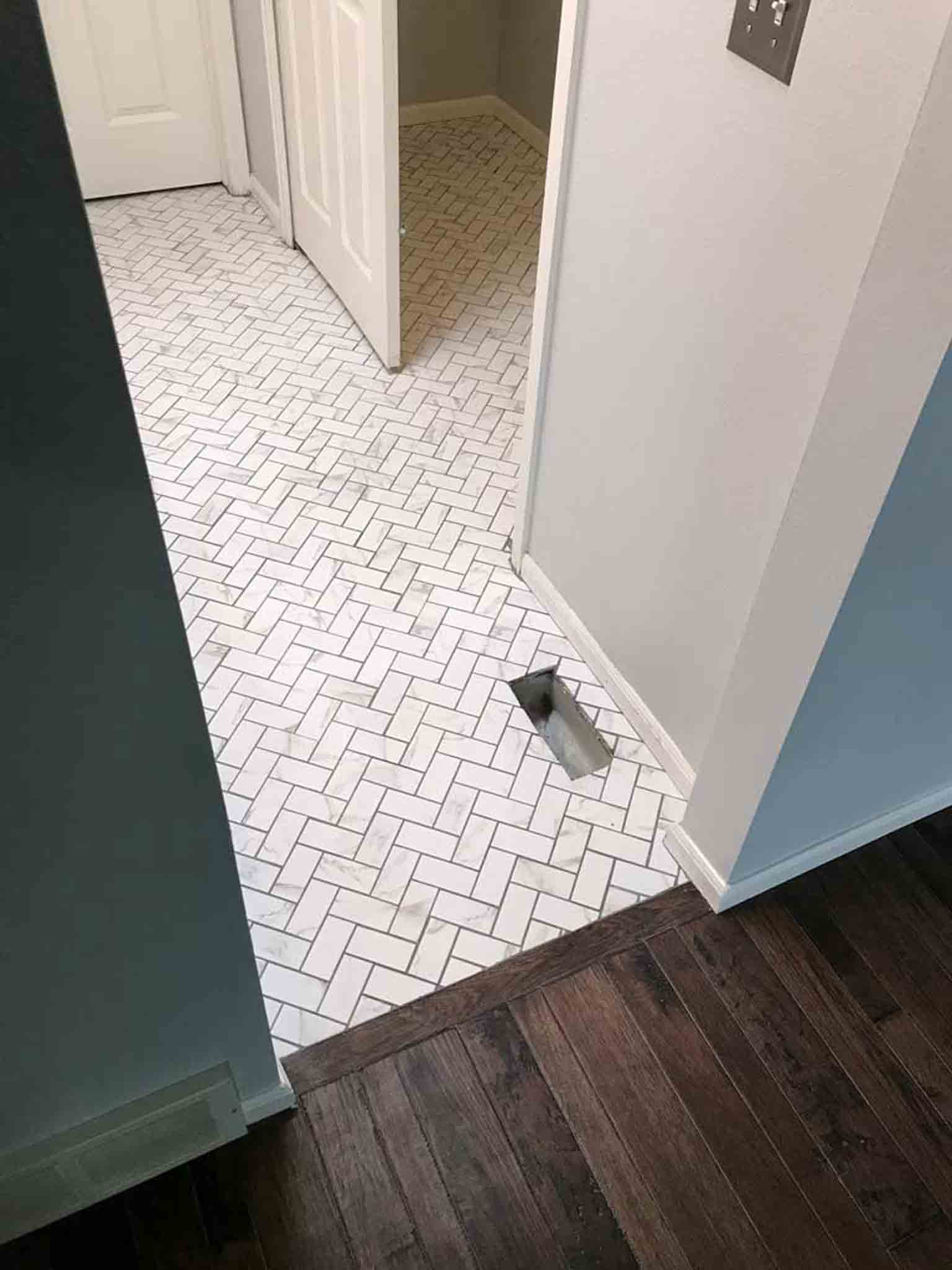 Dark wood flooring leading into a white tile bathroom.