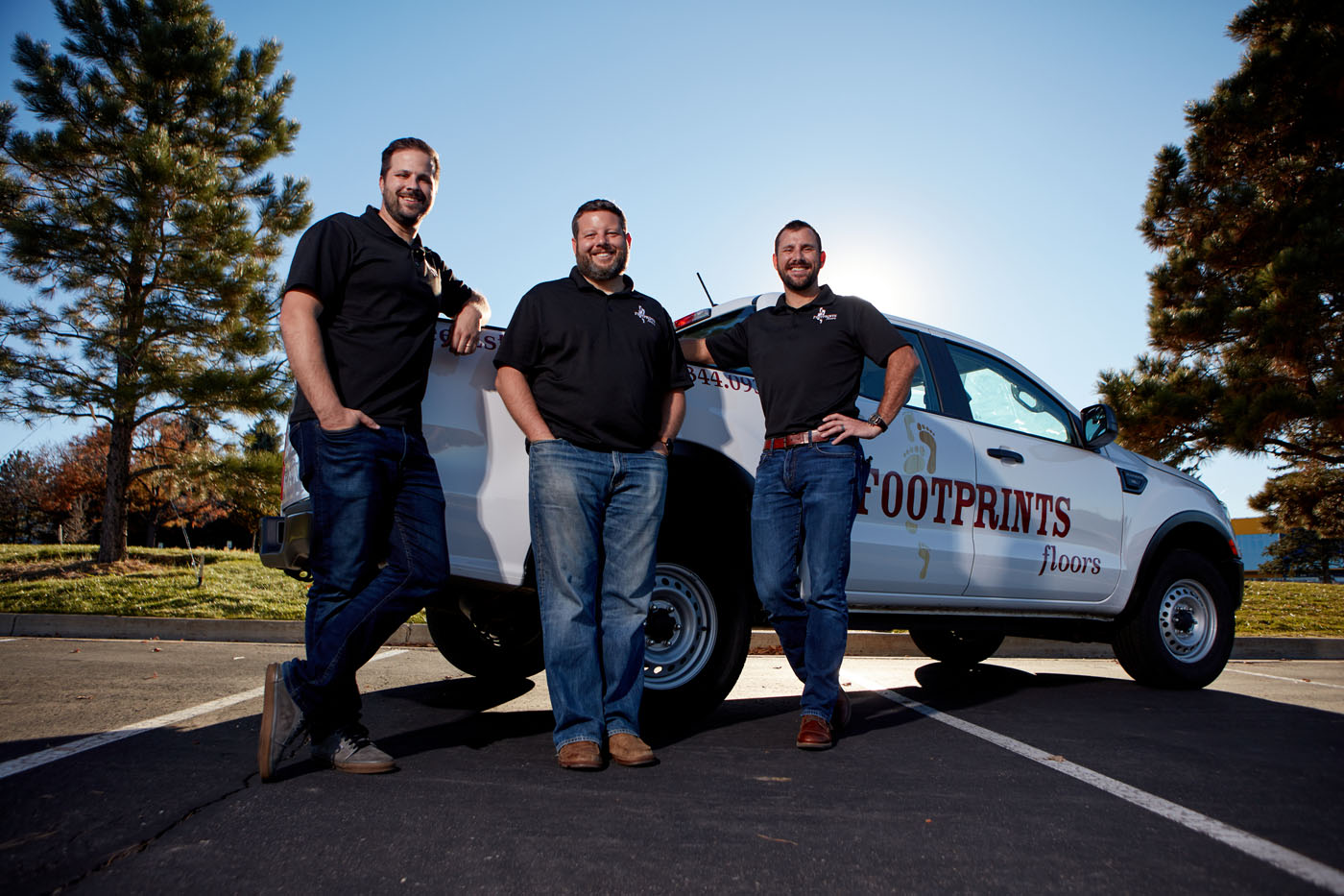 An image of Bryan Park, the founder of Footprints Floors, next to a branded service vehicle and other team members.