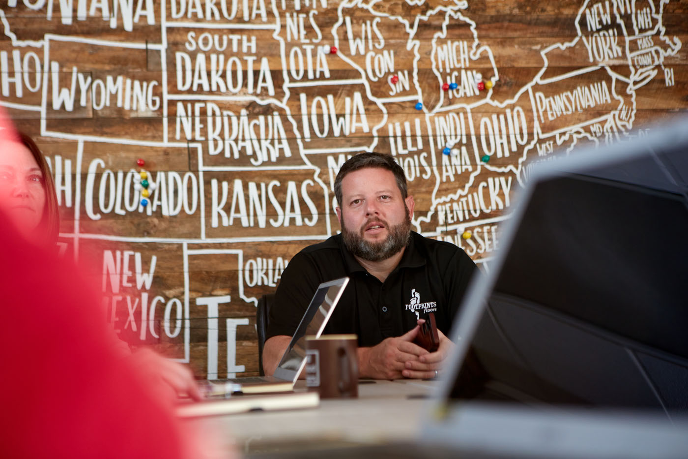 Bryan Park sitting down with other corporate team members - discover the advantages of franchising and why Footprints Floors is a top choice.
