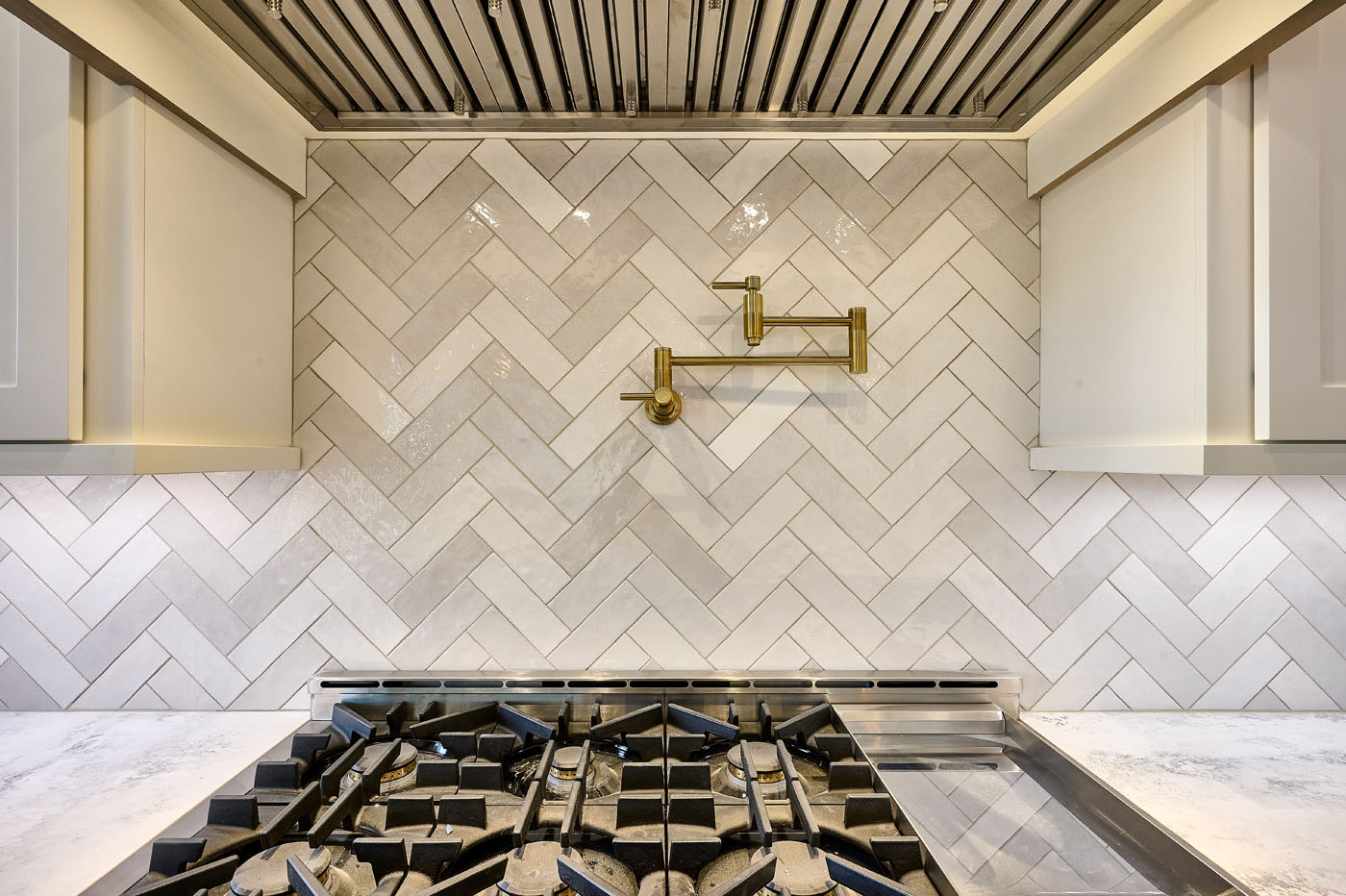 A finished tiled kitchen backsplash with a herringbone design from the expert installers at Footprints Floors Western Nevada .