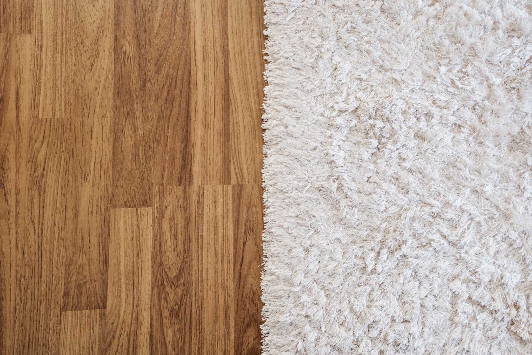 An image of hardwood flooring and carpet side-by-side.