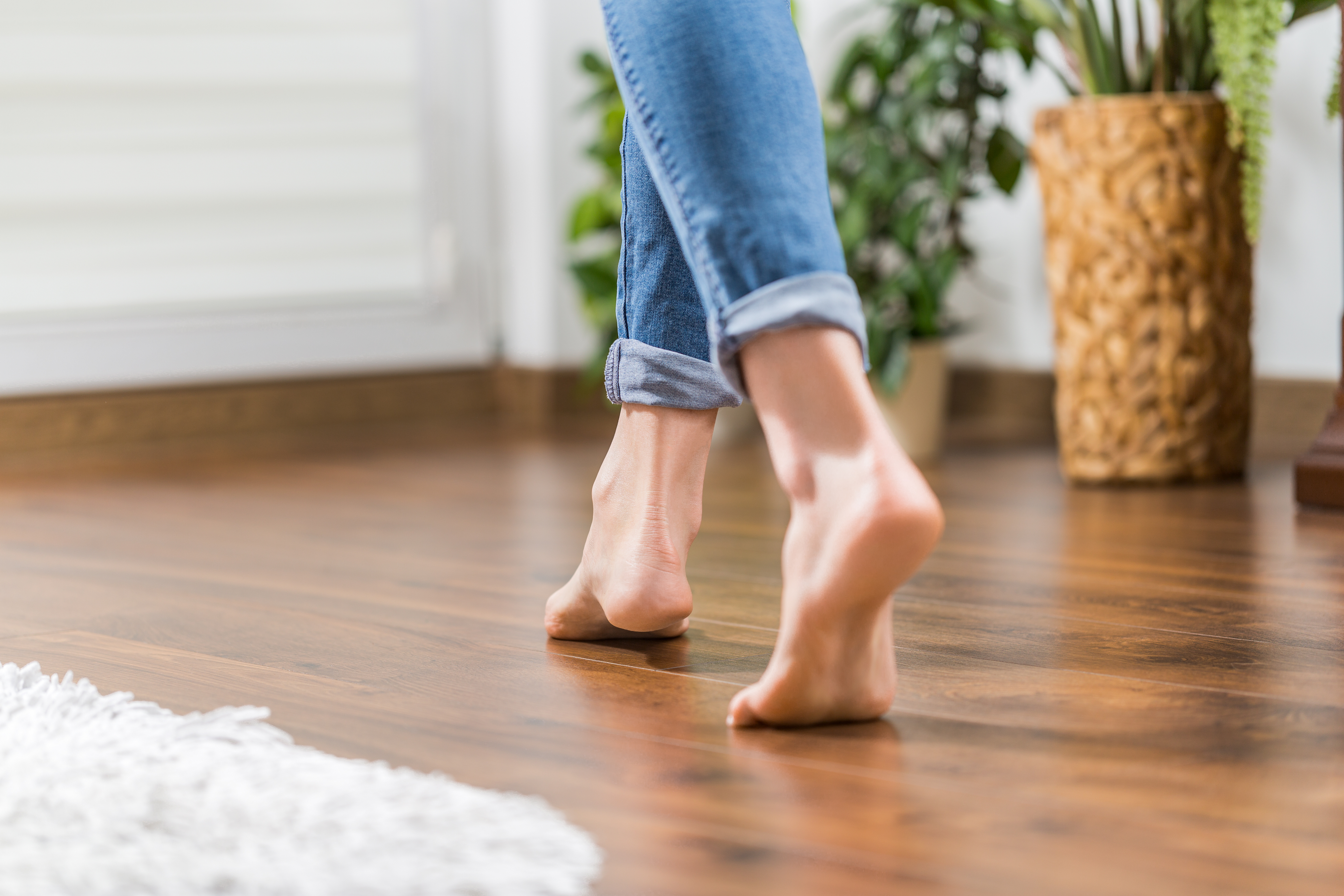 A person walking barefoot on dark hardwood floors installed by the team at Footprints Floors.