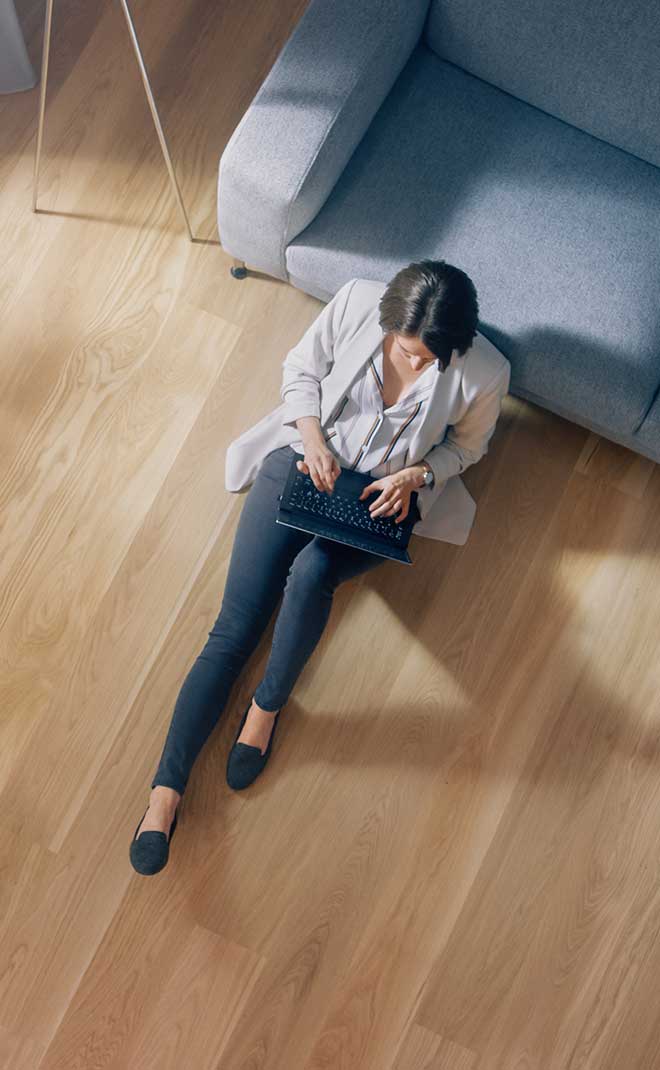 A woman relaxing on her newly installed laminate wood flooring from Footprints Floors.