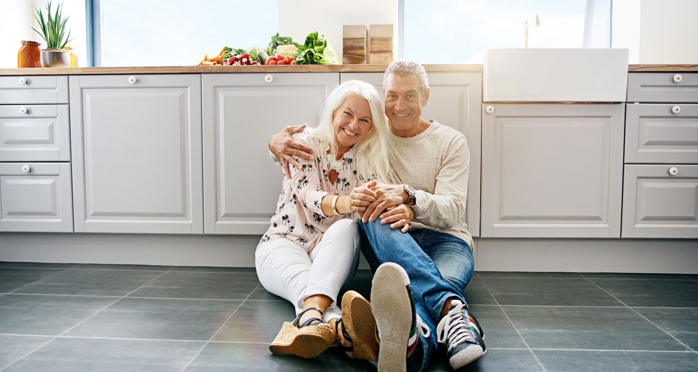 A couple sitting on the floor and enjoying their newly installed stone tiles.