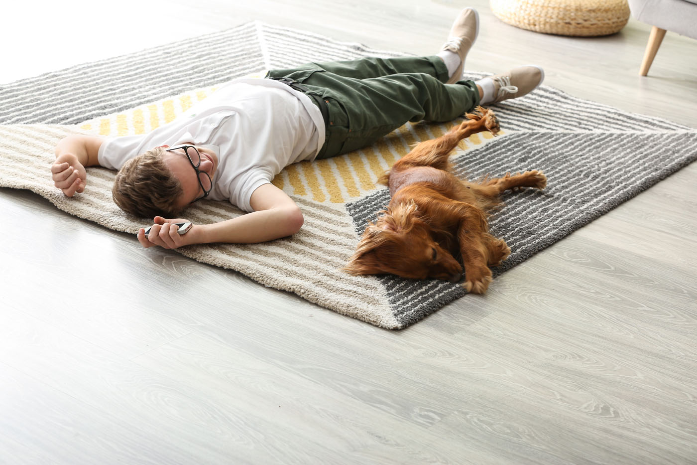 A man and a dog resting on a rug protecting their hardwood floor.