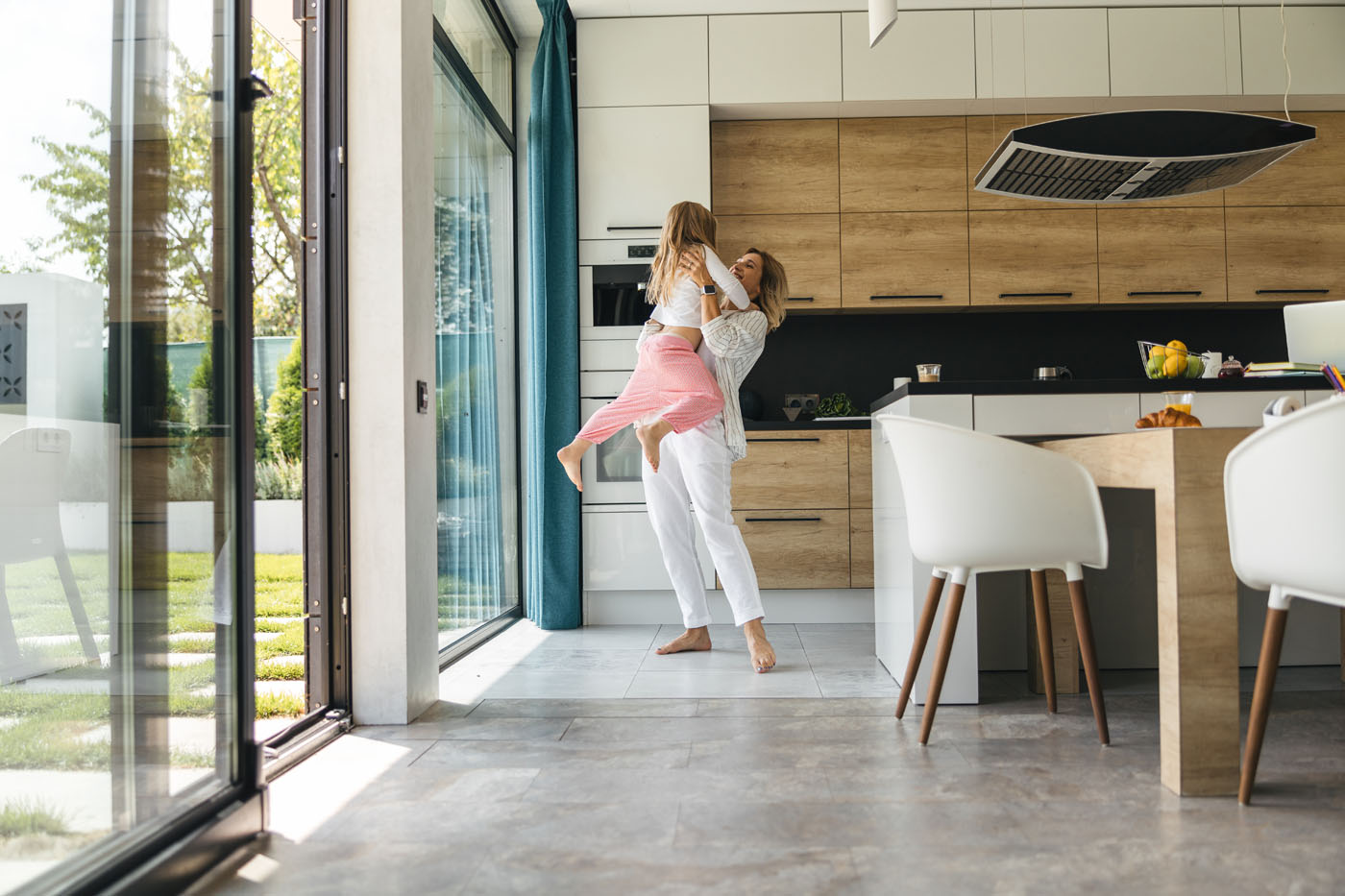 A woman holding her daughter in the kitchen, that has beaitiful tiles installed by Footprints Floors - call today if you are in search of Reno-Sparks Metro tile installers.