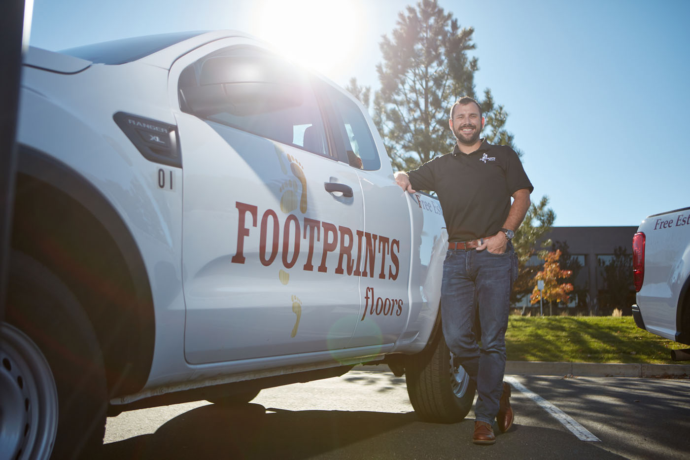 A Footprints Floors technician standing proudly in front of a company truck.