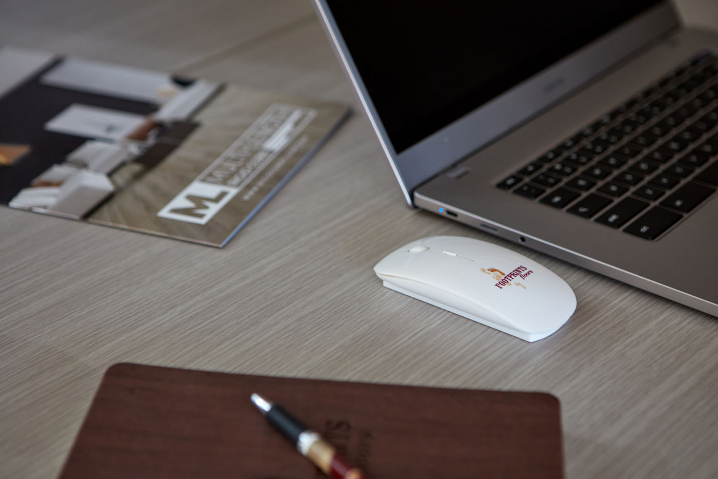 An image of Footprints Floors branded work materials, including a computer, notebook, and mouse.