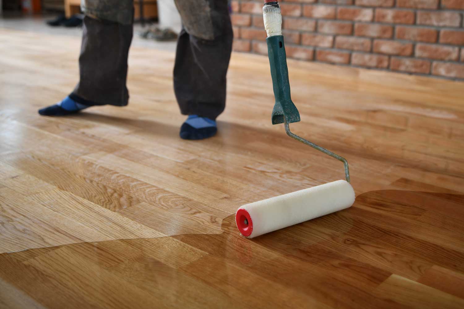 A Footprints Floors Western Nevada  professional applying a water-based finish to hardwood flooring.