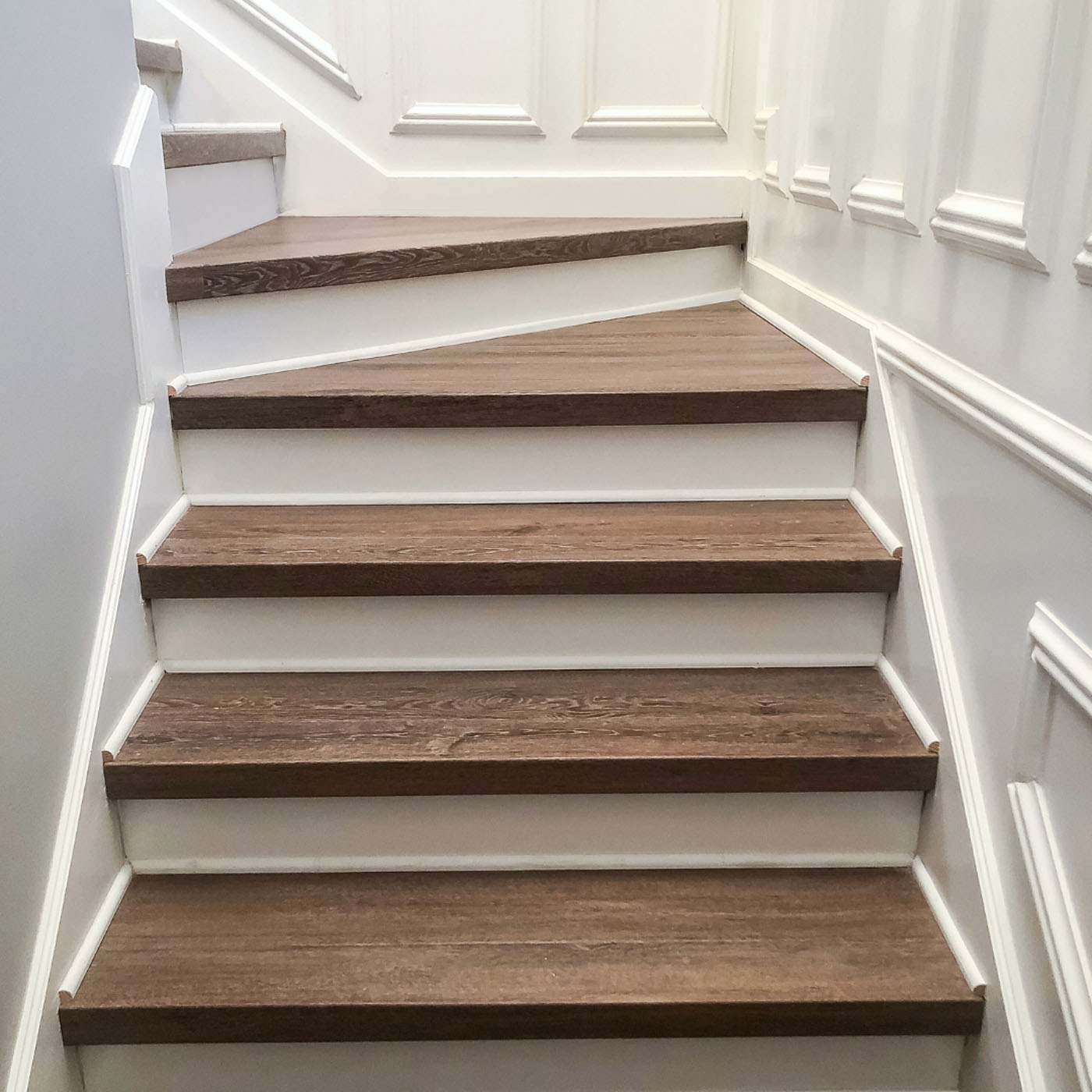A close up picture of laminate stairs installed by the experts at Footprints Floors.